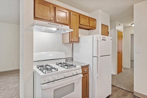 A white stove and refrigerator in a kitchen with wooden cabinets.