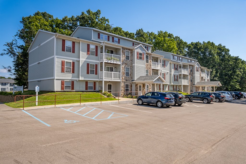 A parking lot in front of a multi-story apartment building with cars parked.