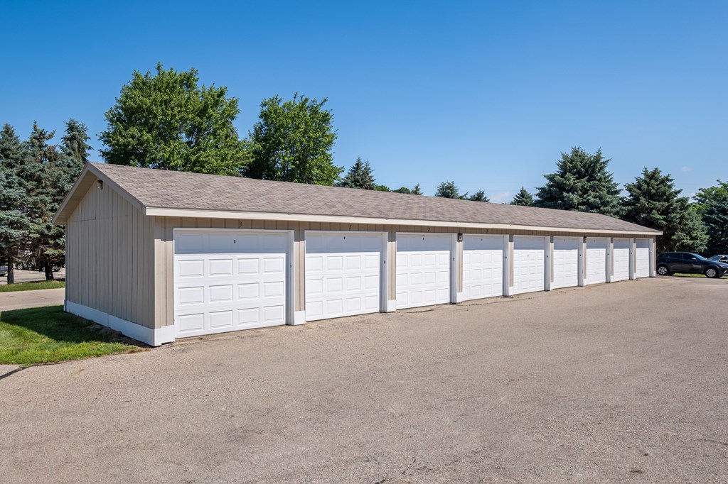 A long white garage with a brown roof is surrounded by a gravel lot.
