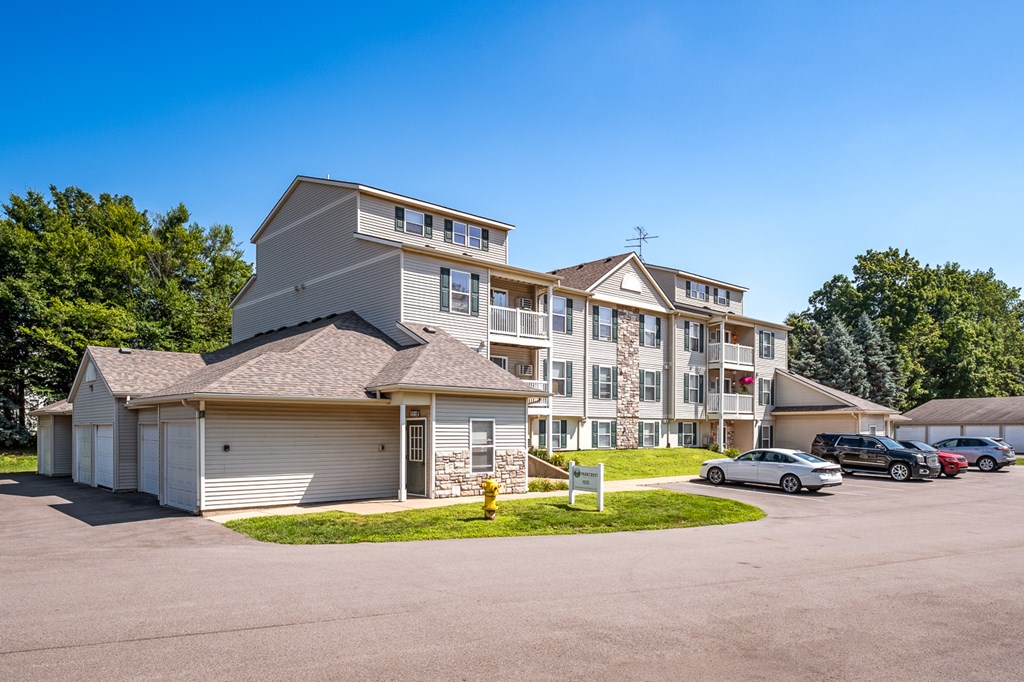 A large apartment complex with multiple buildings and cars parked in the driveway.