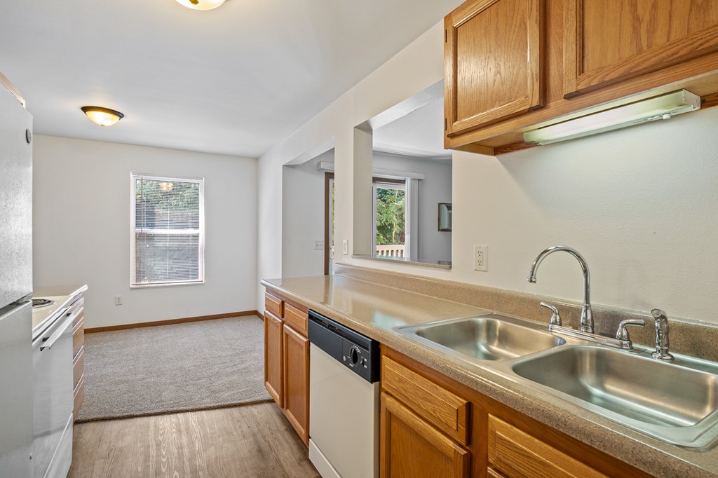 A kitchen with a white fridge, a white dishwasher, and a white sink.