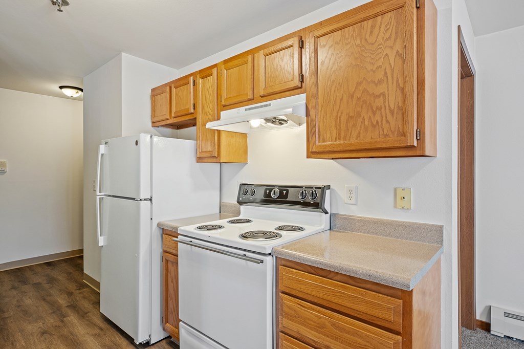 A kitchen with white appliances and wooden cabinets.