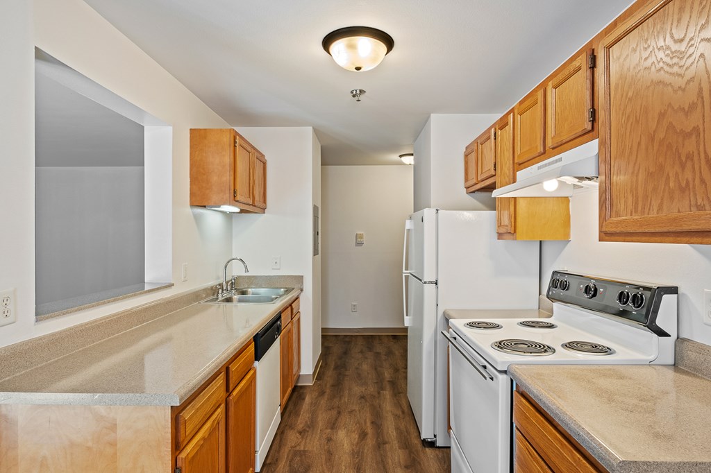 A kitchen with white appliances and wooden cabinets.