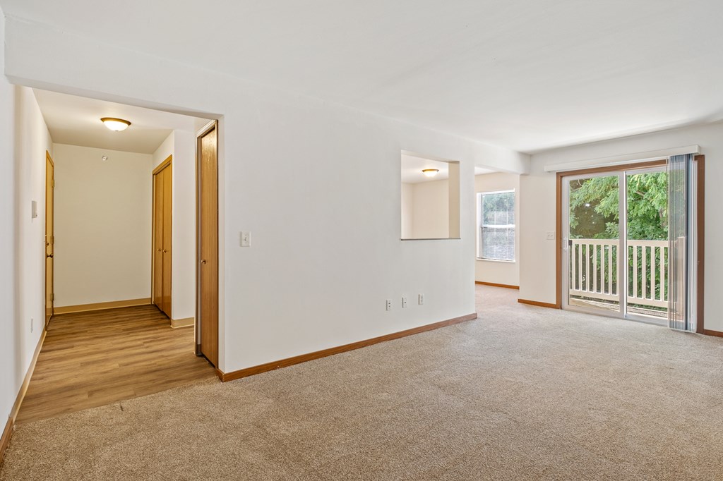A room with a carpeted floor and a sliding glass door leading to a balcony.