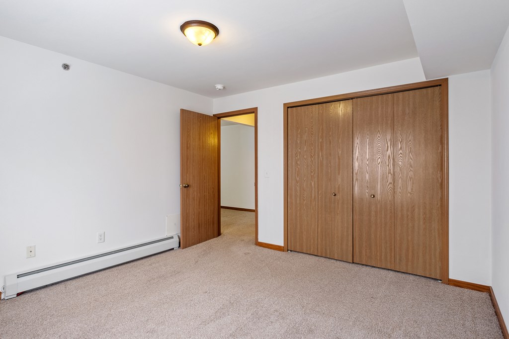 A room with a carpeted floor and two wooden doors.