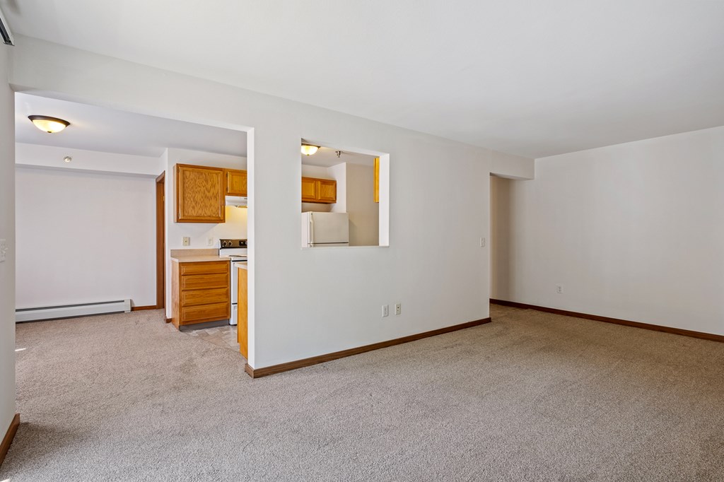 A large empty room with a kitchenette in the corner.