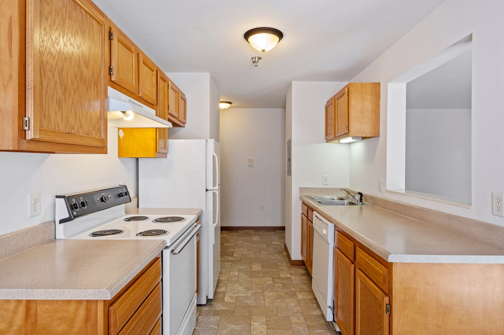 A kitchen with wooden cabinets and a tiled floor.