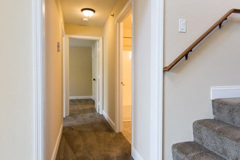 a hallway with carpeted stairs and a hall way with a door to a bedroom