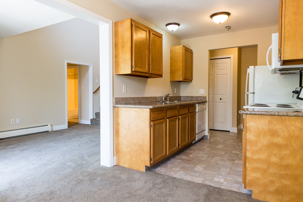 an empty kitchen with wooden cabinets and a white refrigerator