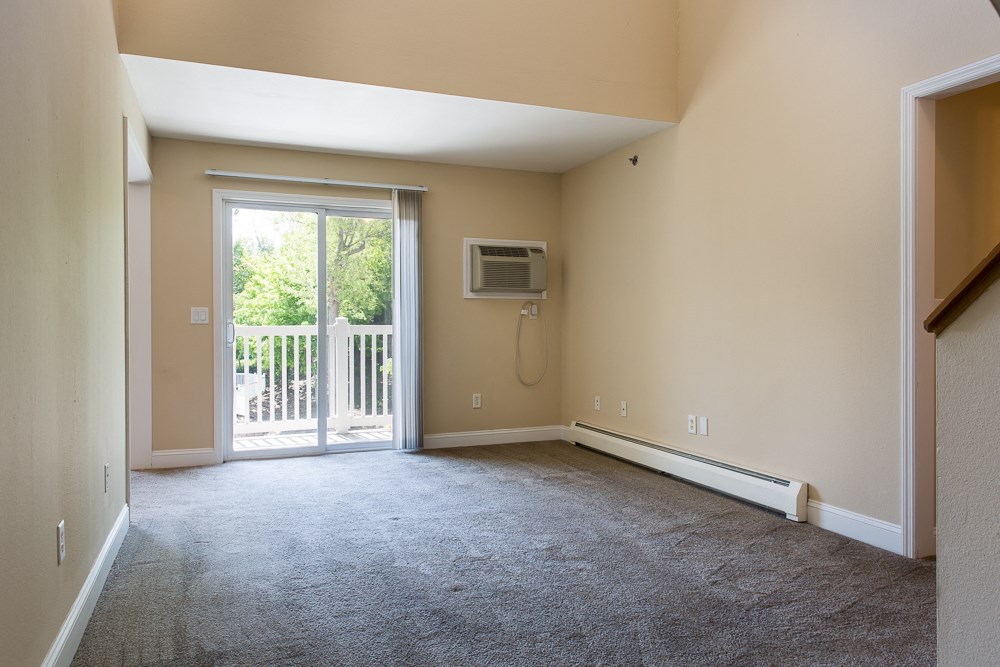 an empty living room with a door to a balcony