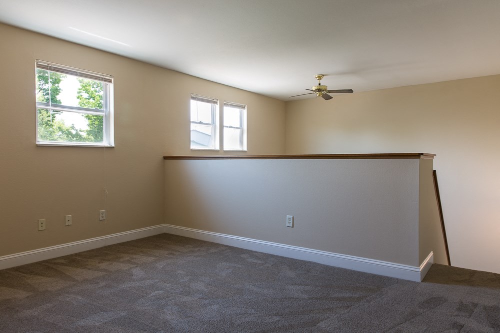 an empty living room with a ceiling fan