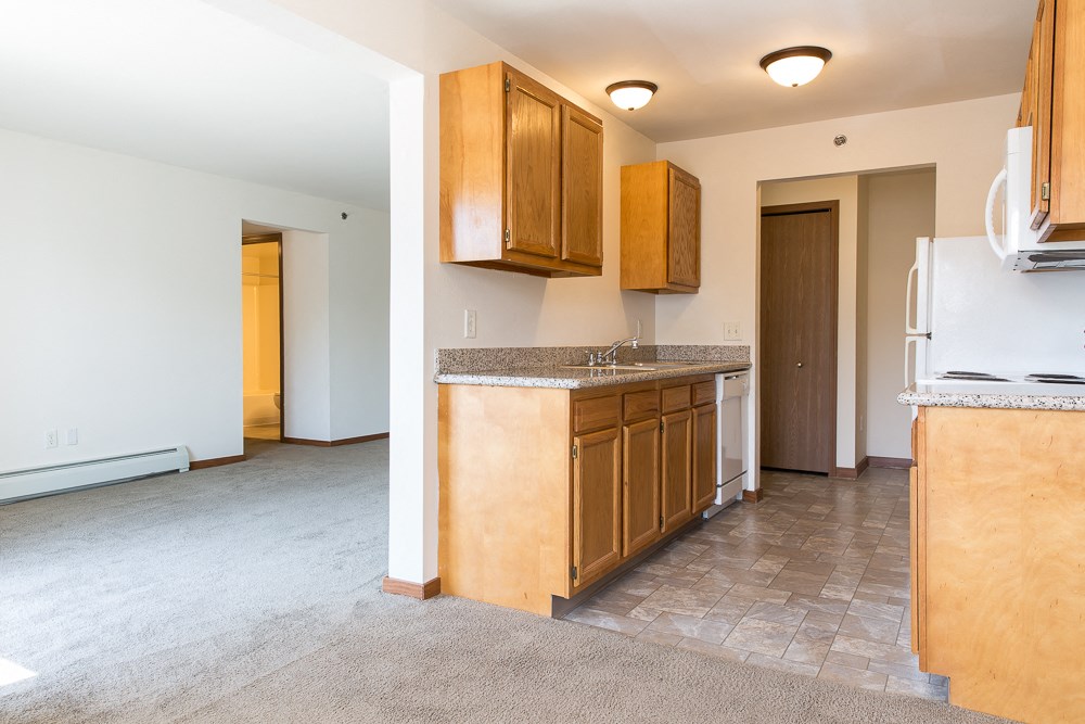 an empty kitchen with wooden cabinets and a white refrigerator