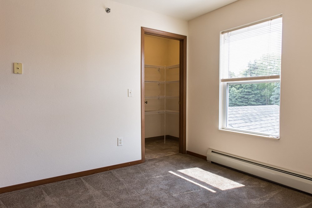 an empty room with a window and a closet