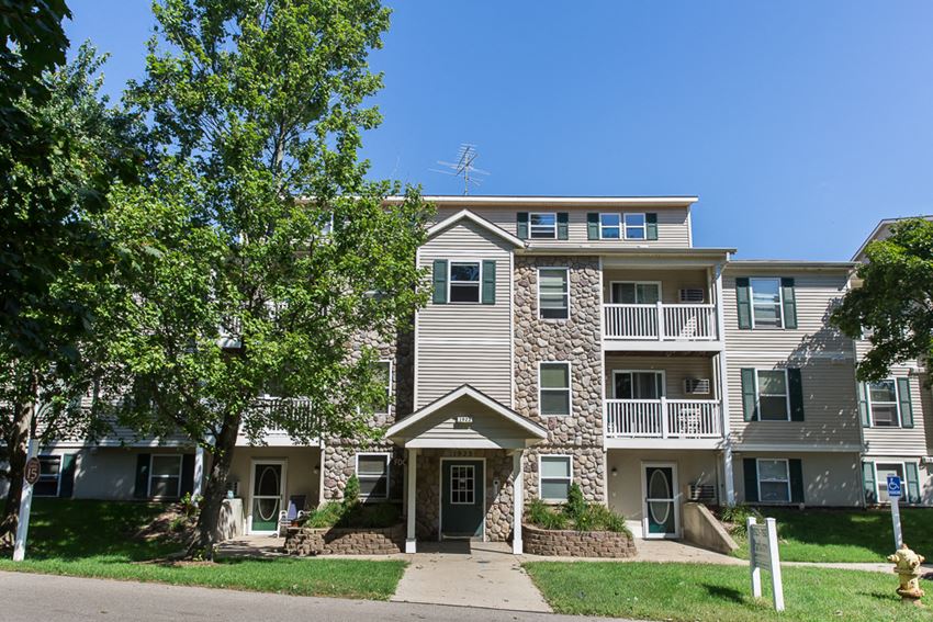 an apartment building with a sidewalk and trees in front of it