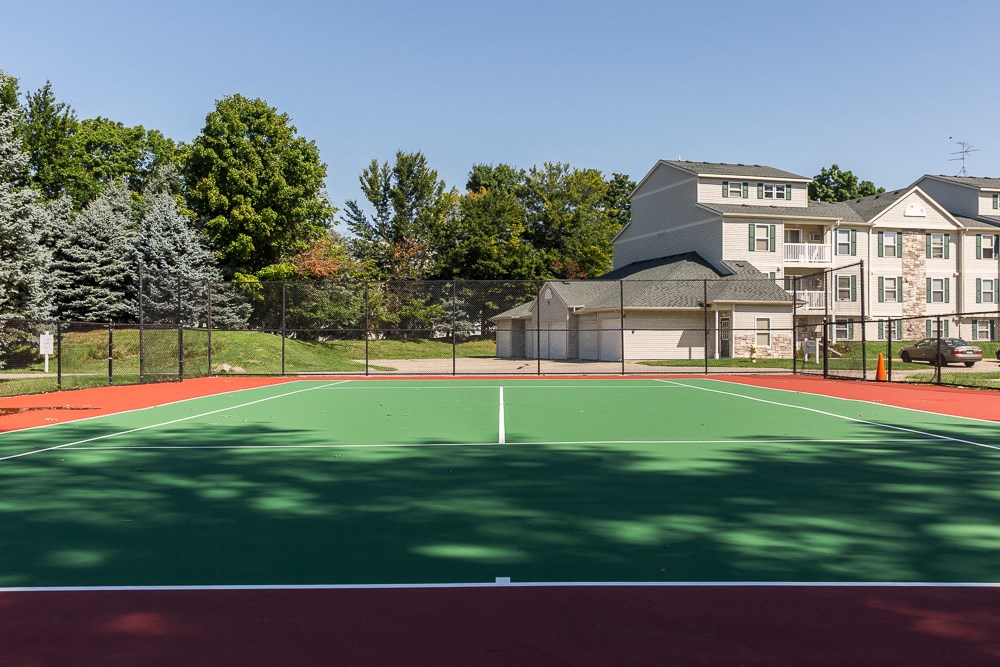 a tennis court with apartments in the background