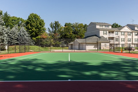 a tennis court with apartments in the background