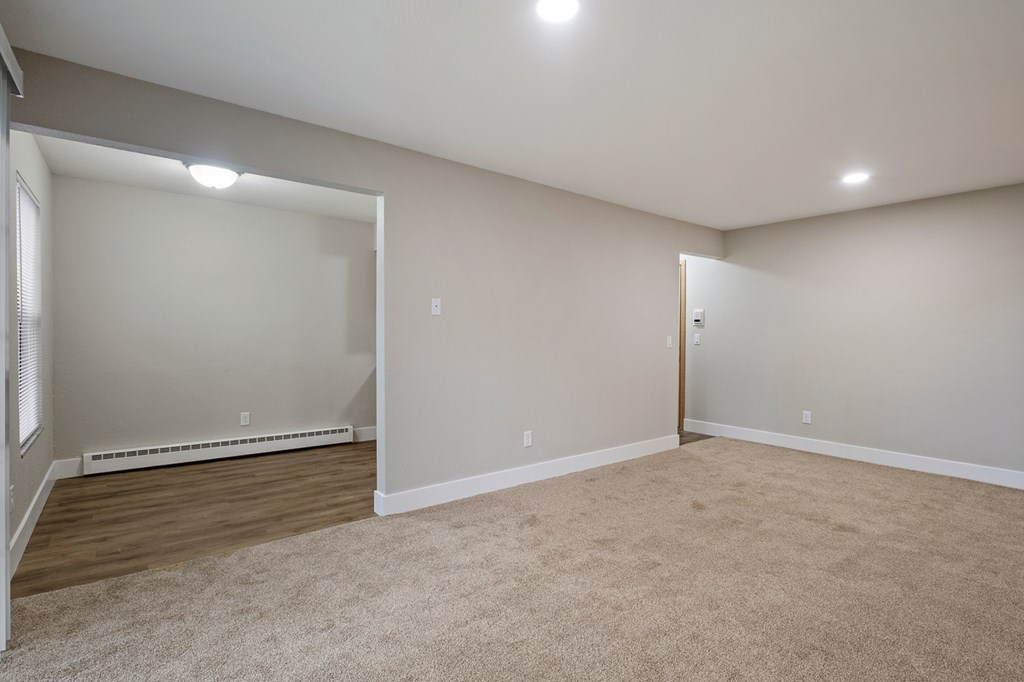A room with a carpeted floor and a door on the right side.