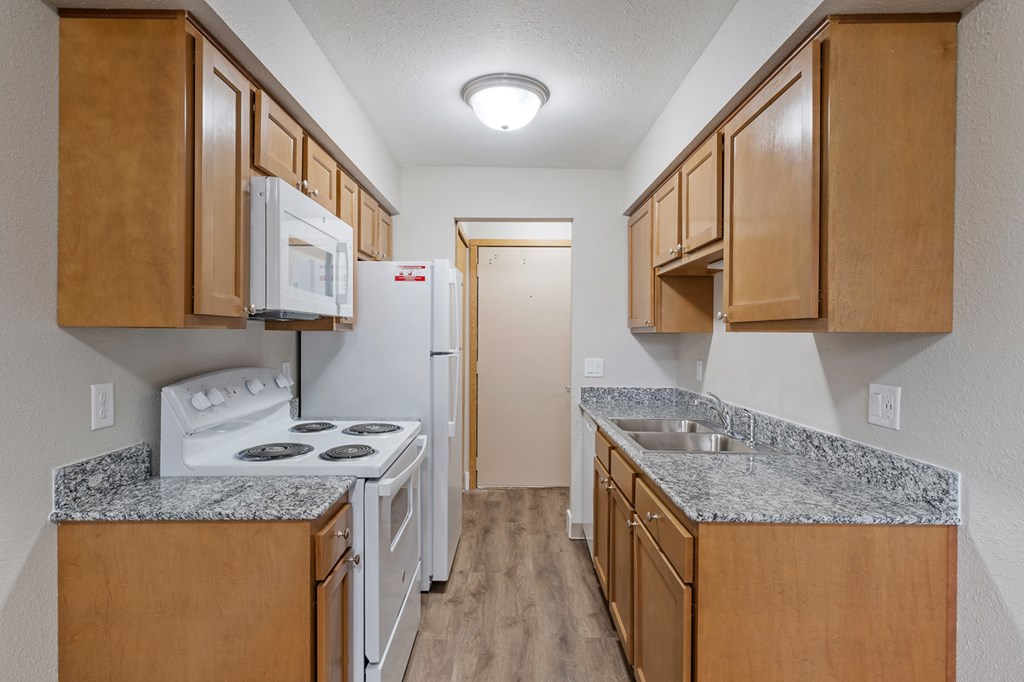 A kitchen with a white stove and refrigerator.