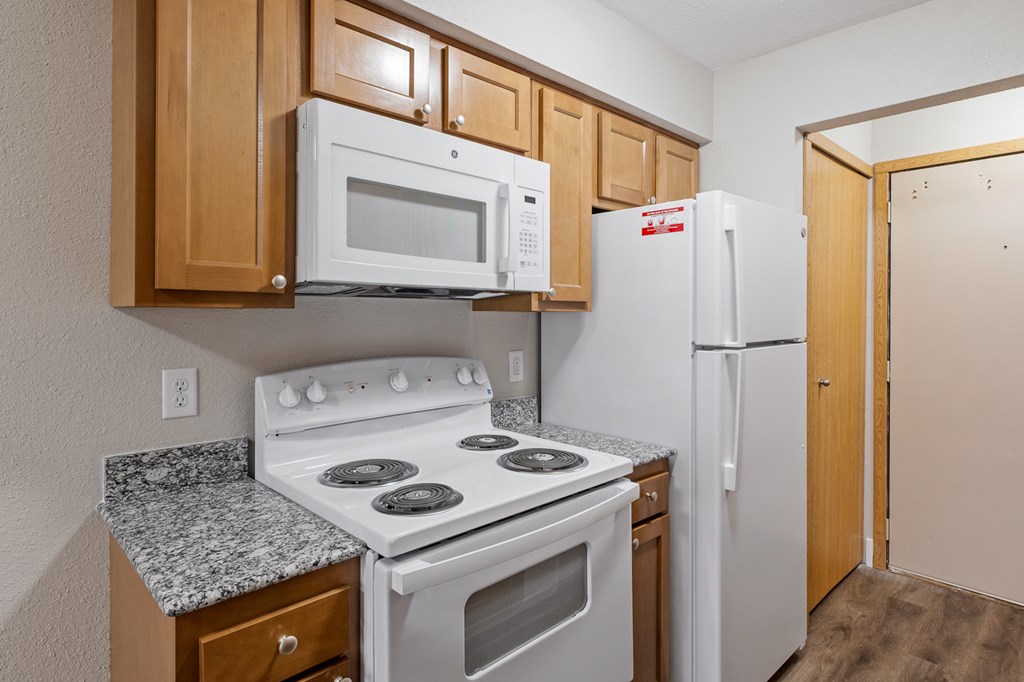 A kitchen with a white stove top oven, a white microwave, and a white refrigerator.