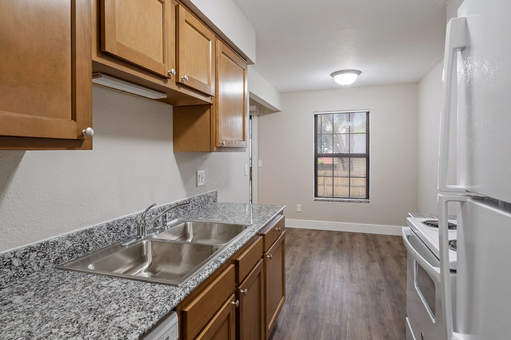 A kitchen with granite countertops and wooden cabinets.