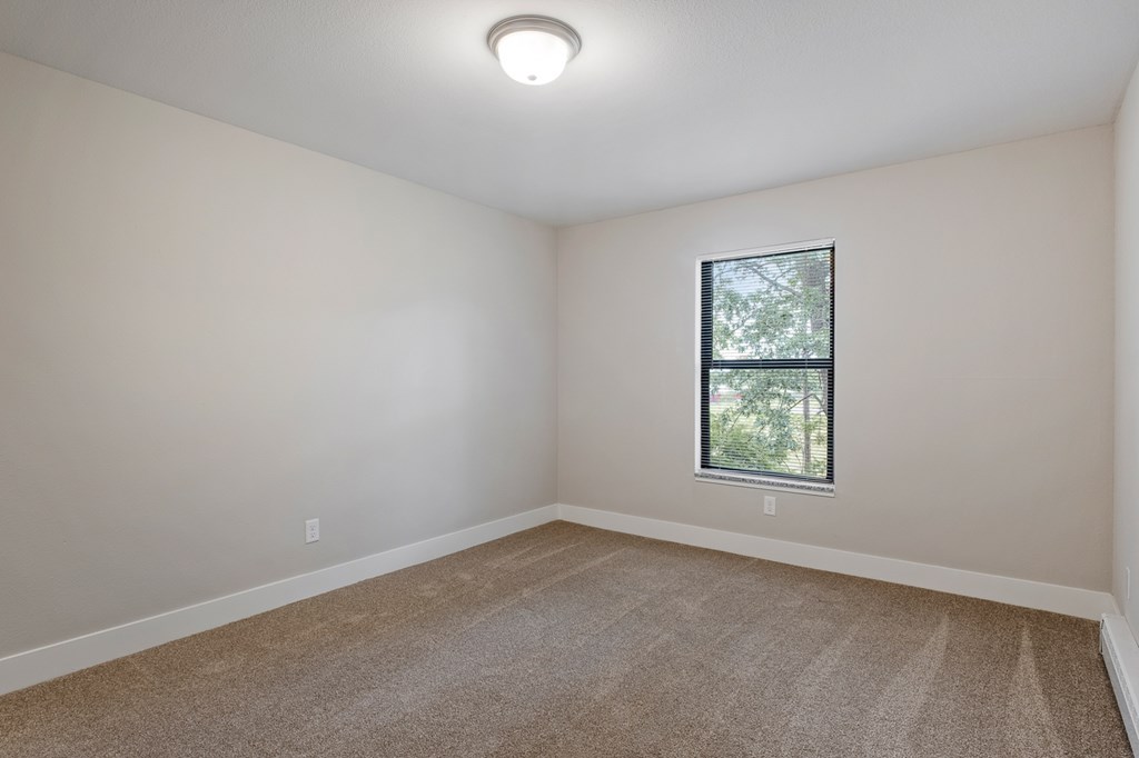A room with a window and carpeted floor.