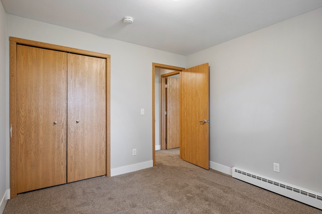 A room with two wooden doors and carpeted floor.