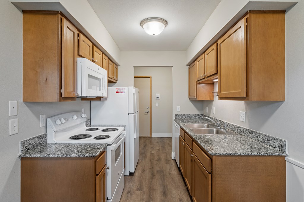 A kitchen with white appliances and wooden cabinets.