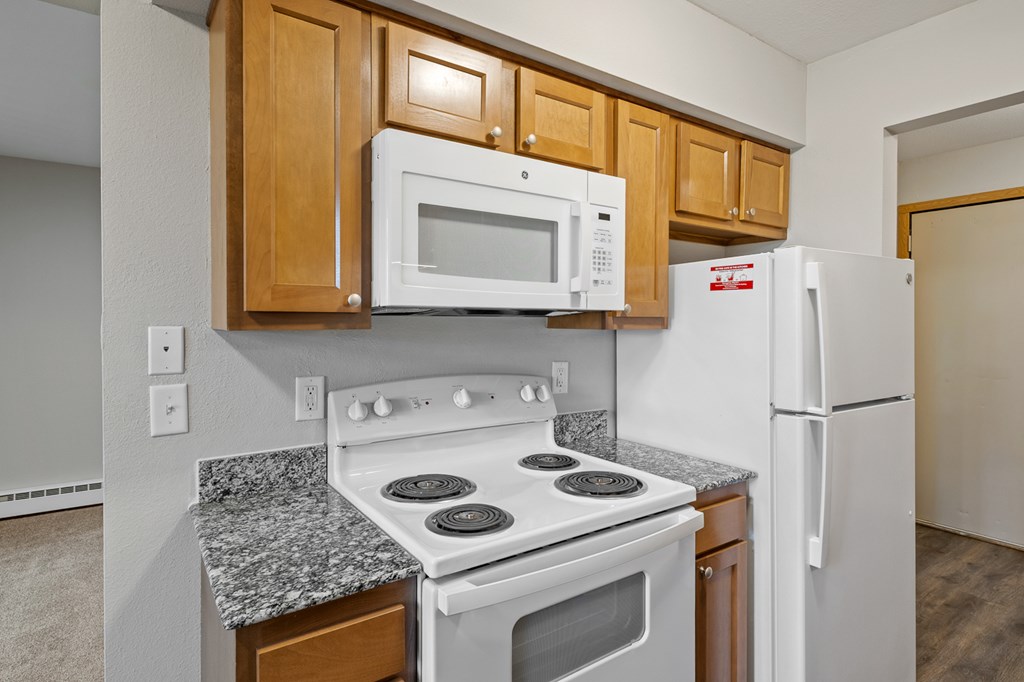 A kitchen with a white stove and a white refrigerator.