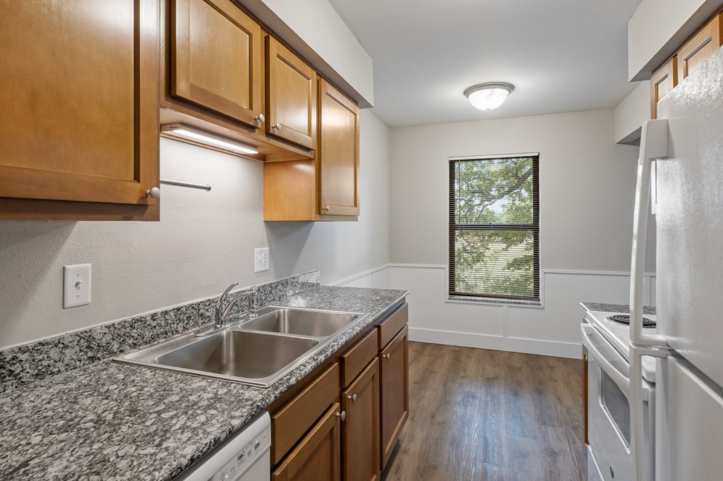 A kitchen with wooden cabinets and a granite countertop.