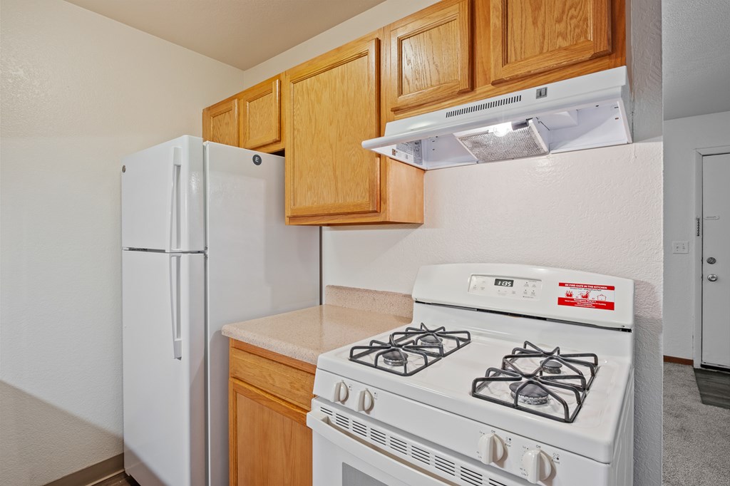 A white stove with a red sticker on it is in a kitchen with wooden cabinets.