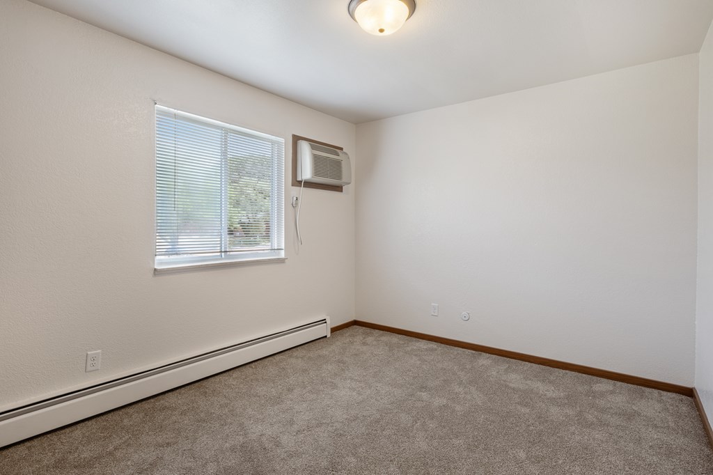 A room with a window and an air conditioner unit on the wall.