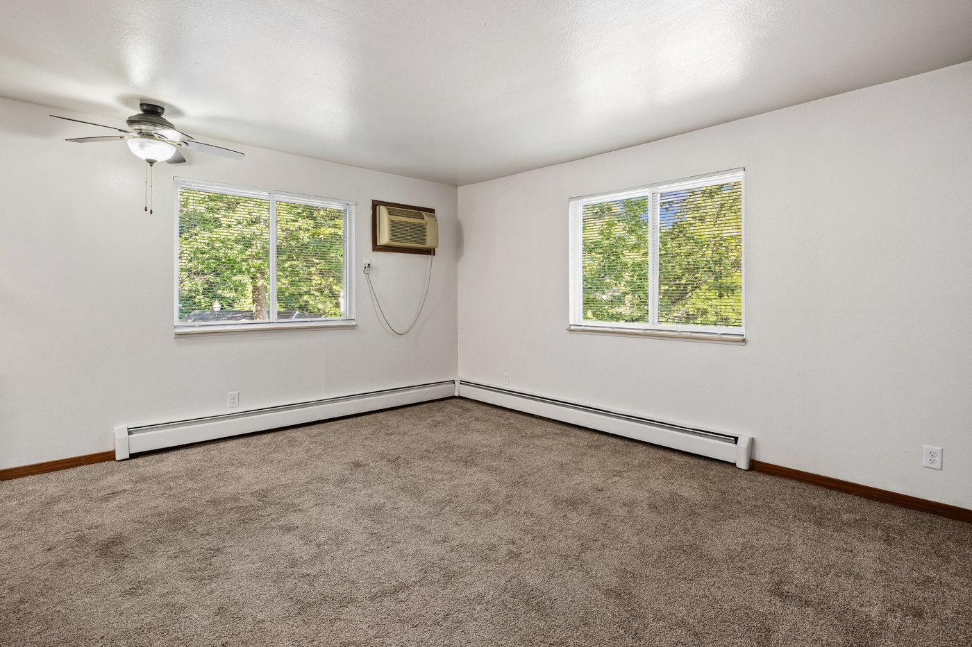 A room with a ceiling fan and two windows.