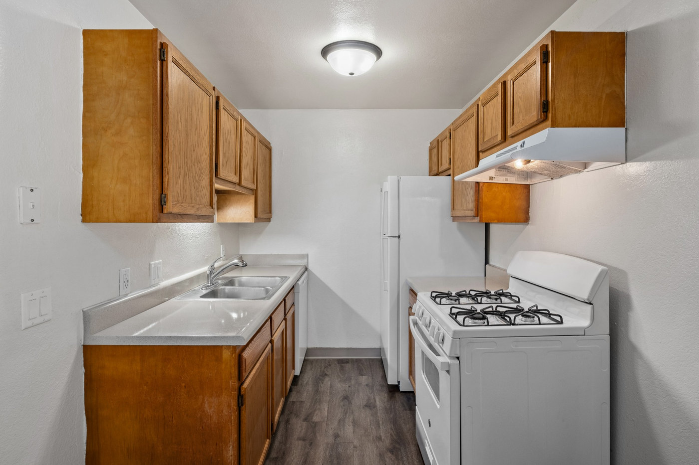 A small kitchen with a white refrigerator and a white stove.