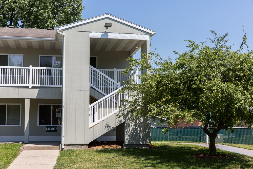 A tree is in front of a two-story apartment building.