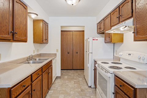 A kitchen with wooden cabinets and a white stove top oven.