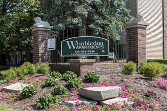 the front yard of the wimbledon apartments sign in front of a brick building