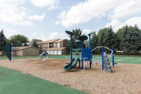 A playground with a green slide and a basketball hoop.