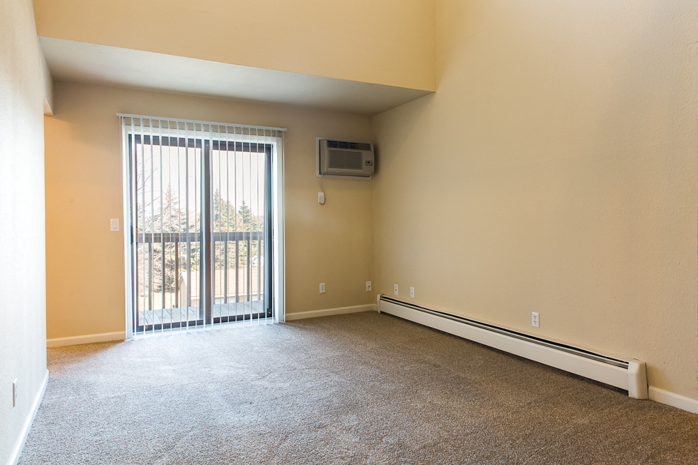 an empty living room with a sliding glass door to a balcony