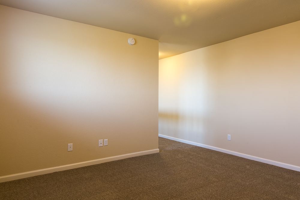 an empty living room with white walls and carpet