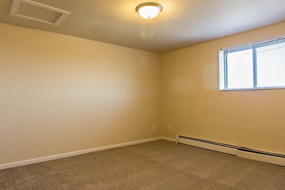 an empty living room with a window and carpet