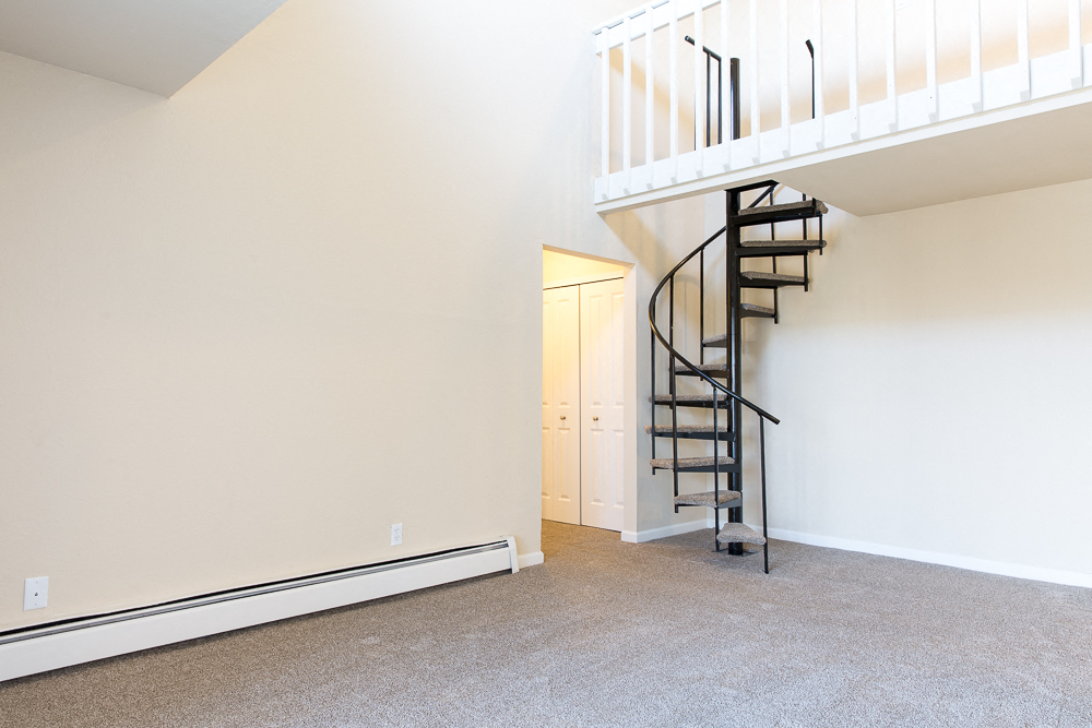 an empty living room with a spiral staircase in a house