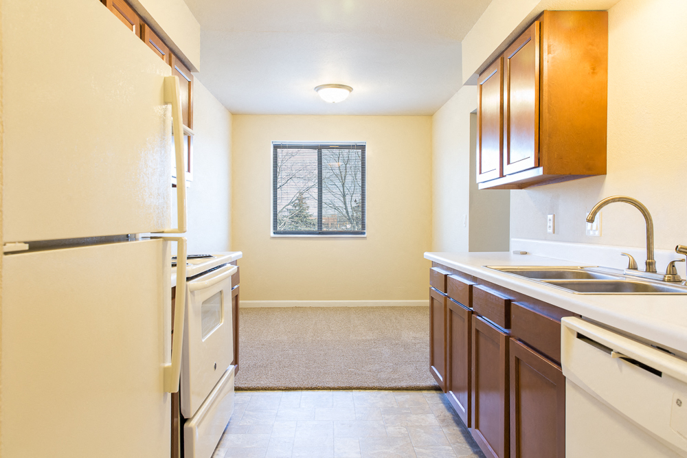 a kitchen with white appliances and wooden cabinets and a window