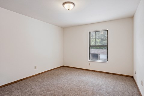 A room with a window and carpeted floor.