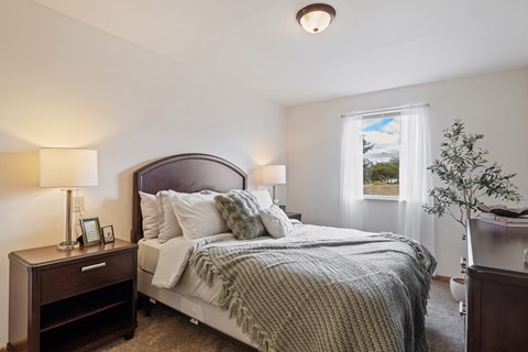 A bedroom with a large bed and a nightstand with a lamp.