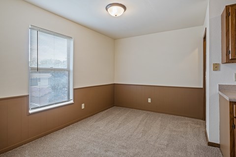 A room with a window and a carpeted floor.