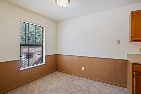 A room with a window and a carpeted floor.