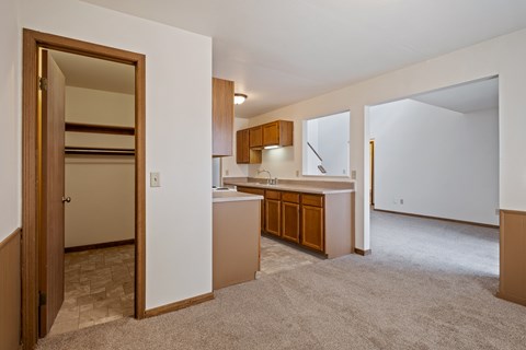 A kitchen with white walls and wooden cabinets.