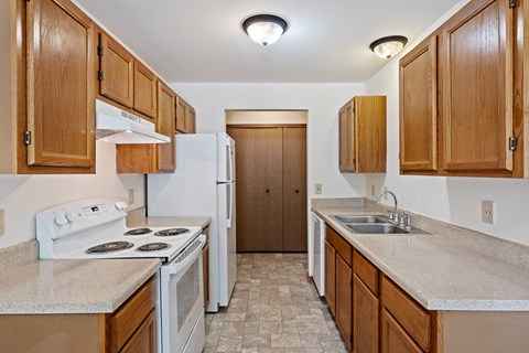 A kitchen with white appliances and wooden cabinets.