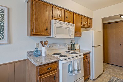 A kitchen with a white stove top oven and a white refrigerator.