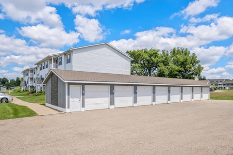 A large white building with a grey roof and a car parked in front.